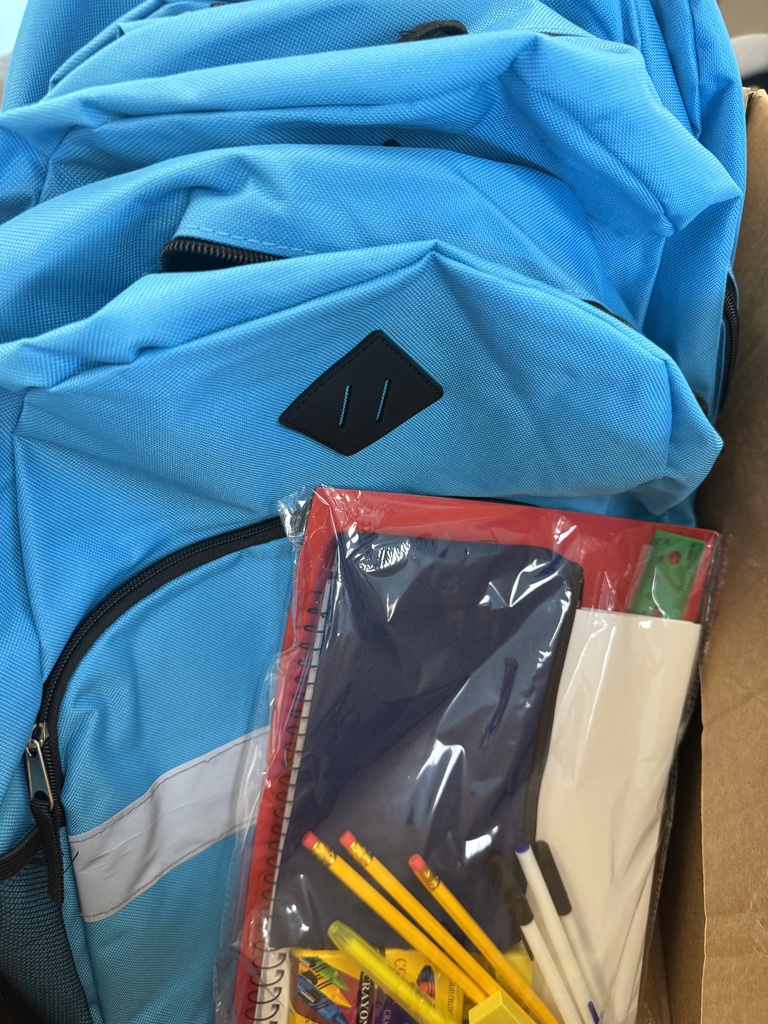blue backpack with a package of school supplies including folders, pencils, pens, crayons, ruler