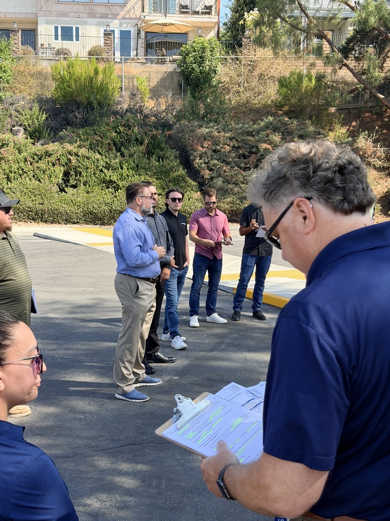 a man holds a clipboard with paperwork while other individuals look on