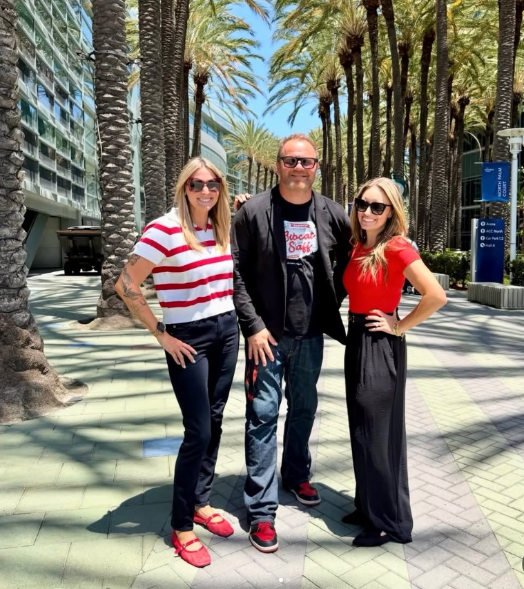 three people stand in the center of palm trees