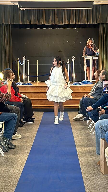 girl walks down runway stage with white plastic bag dress