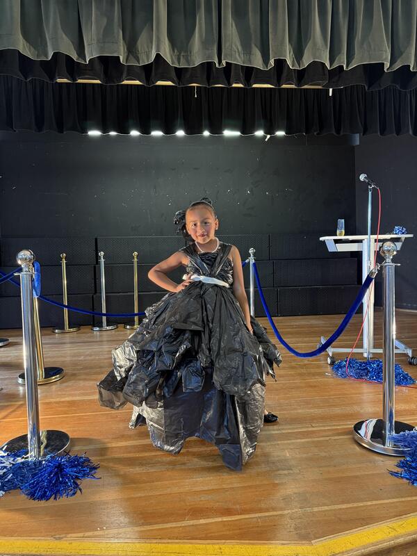 girl walks down runway in black trash bag dress design