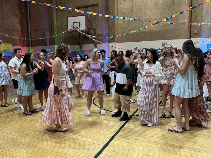 people dancing in a gym with colorful streamers above them