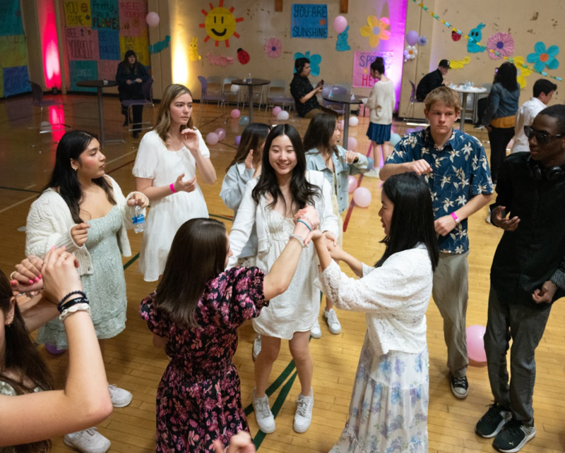 girls dancing in a gym with colorful lights and posters behind them