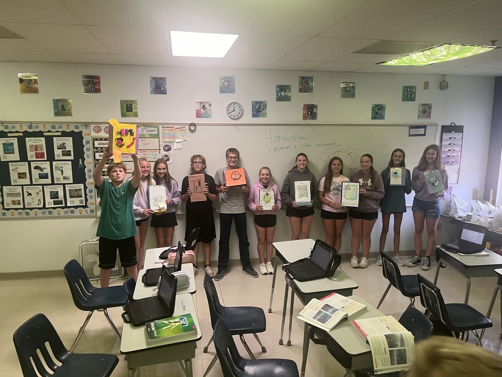 7th graders posing with their finished cereal box cell projects 