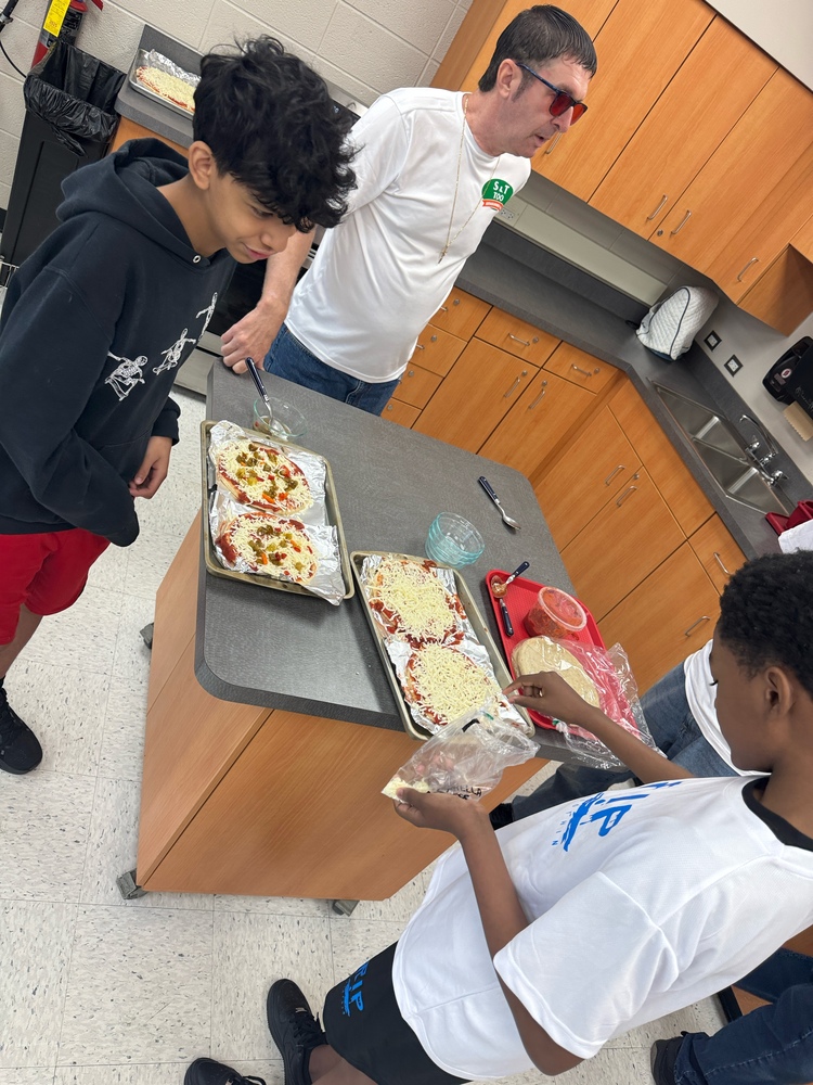 A Bremen High School student assembles personal pizzas with guidance from Hillcrest High School teacher and S&T Pizza co-owner Ed Schodrof during a hands-on learning activity. Students practiced following recipes, identifying ingredients and preparing food as part of the collaborative event.