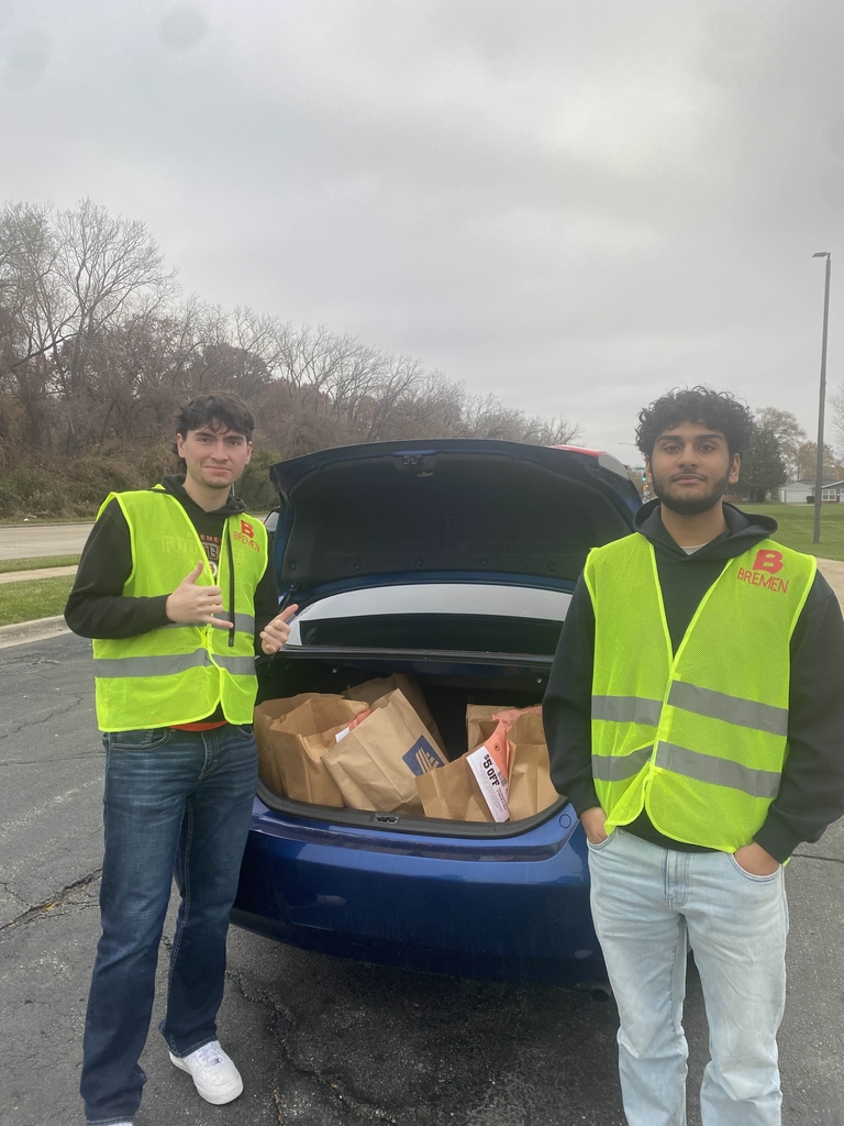 2 Volunteers for food drive next to car full of food