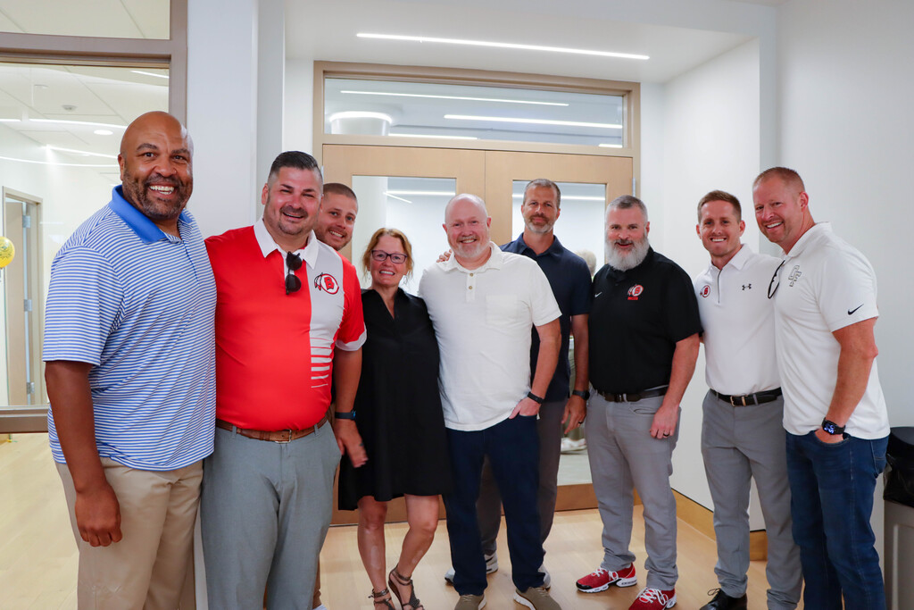 **Alt text:** A group of Bremen High School District 228 administrators, athletic directors, and coaches pose together inside the new Administration Center during the ribbon-cutting celebration. The group smiles for a photo in front of the entrance to the District's first-ever board room, highlighting the collaborative spirit of the event.