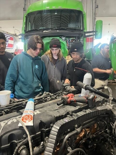Students examine a truck engine during a behind-the-scenes tour of the CIT Trucks facility.