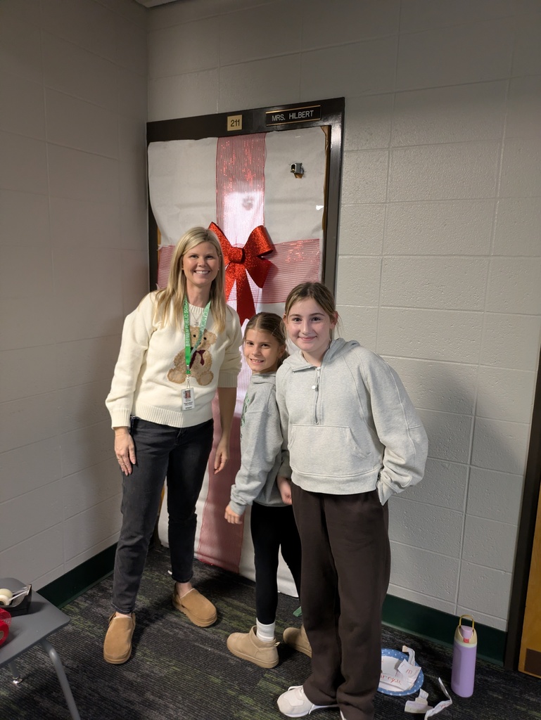 3 Girls decorating a door with a bow on it