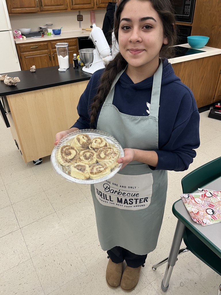 BHS Student Holding a plate of uncooked  cinnamon rolls to take home and bake.