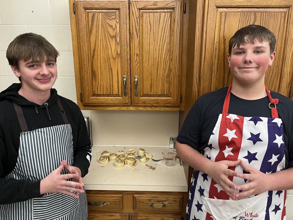 BHS Stuents standing by a counter making cinnamon rolls to take home.