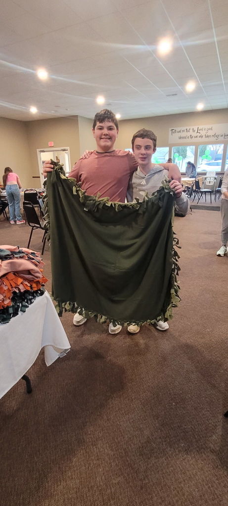 2 boys holding up a  green blanket