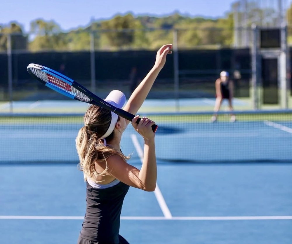 Lexie McDaniel throwing up tennis ball to start a set