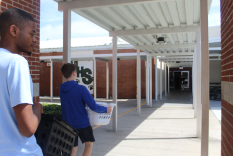 School spirit and funny sights in the halls. Senior Kyle McLaren walks through the halls carrying a storage container filled with all of his school supplies, while another student is passing by participating too. Students got to show off their creativity and school spirit with unique and funny ideas. Photo credits: Paige Allen