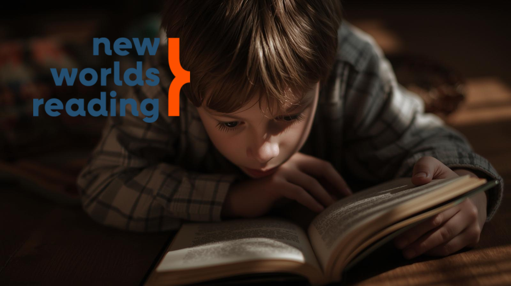 Boy laying down reading a book. New Worlds Reading.