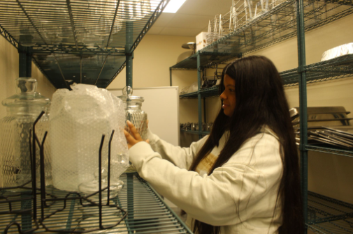 Everything Has A Place: Junior Kerollen Mendes Ferreira Dos Santos packs away glassware in the new culinary storage closet. The new closet was one of the items added to the culinary lab during the summer renovation, and with metal shelving and new LED lights, students could easily retrieve items from the storage room. “[The closet] feels more like a real kitchen now, so it makes us take it more seriously,” said Mendes Ferreira Dos Santos. Previously, the culinary lab had cabinets to store equipment and glassware in, which made working difficult. “With the new and redesigned classroom/dining room floor plan and dedicated storage area, we are better organized and able to practice and operate with the same standards as the food-service industry,” Chef Michael Ferguson said. Photo by Kyle McLaren