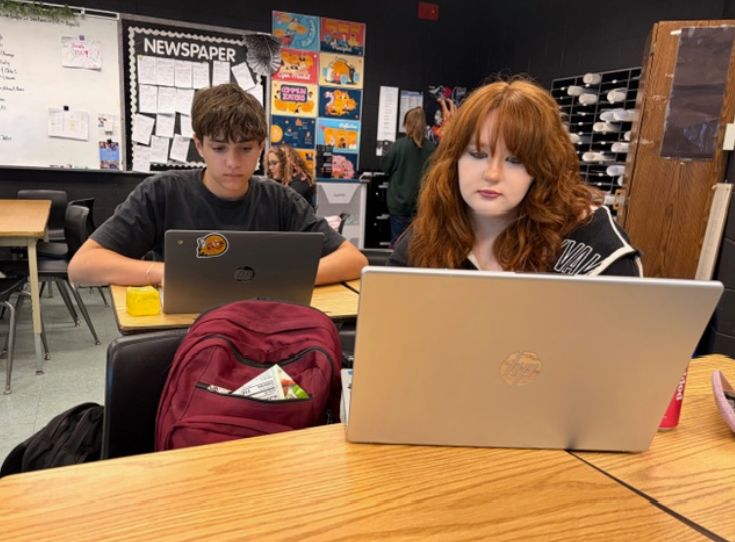 Caption: Typing Away. Ava Brouard types on her laptop during 4th-period Newspaper as she works on developing her deadline. Brouard, a freshman in her first year on the staff, learned how to research, interview, and write alongside her classmates in the Mrs. Reynold’s classroom. She said the class had already become a experience for her, explaining, “This year is my first time ever being in it, but it’s something I’ve always wanted to do.”. Photo by Issy Perez