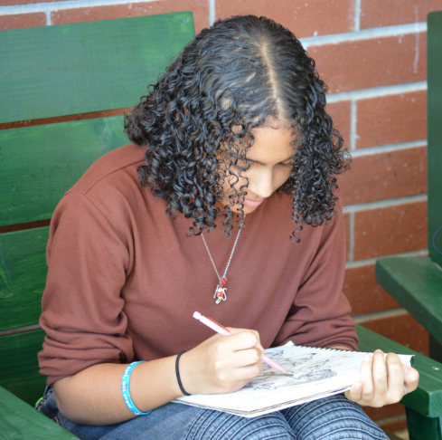 Articulating Amazingly For Art: Symphony Williams practices during her Lunch Period on one of her notebooks. Williams strived for an Arts Education, or just an Education major, as she continued to work through her beginning two years of college during her sophomore and now junior year. “I want to be a High school art teacher… I want to be someone the kids can rely on, and I want them to be comfortable in my room. I’ll be a fun but fair teacher,” said Williams. Photo by Tyler Ferreira Alves Hill.