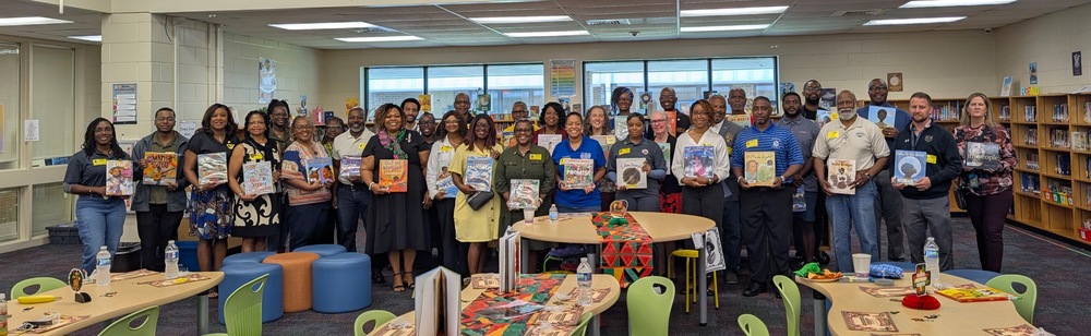 Community volunteers gather in the Columbia Elementary media center holding books by African American authors during the school’s African American Read-In.