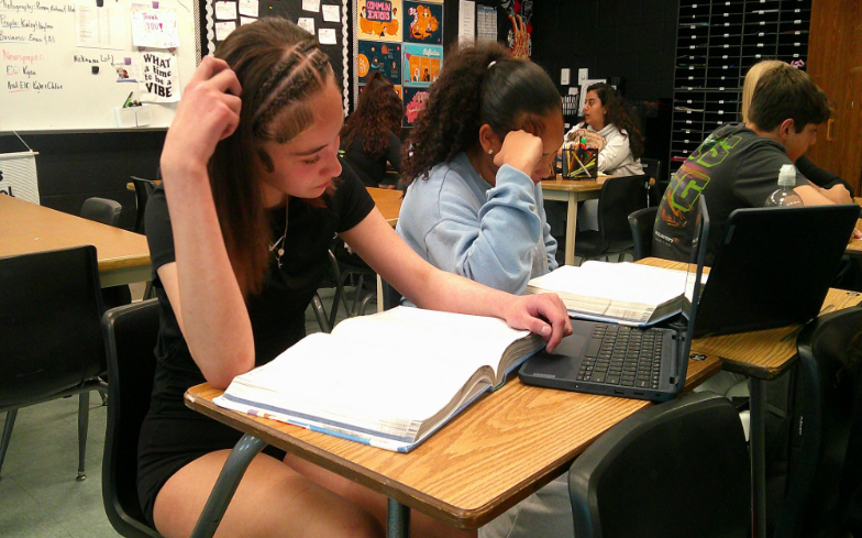 Caption: Working Together: In a busy classroom, two students, Aubrianna Presley and Samiyah Evans, work together at a table as they focus on all the recent assignments. Focused on completing the assignments they collaborated on class work to strengthen their understanding of the lesson. Pressely said, “The Odyssey has shown me a lot of things and it was fun to learn about.” Photo Credit: Anabella Mulligan