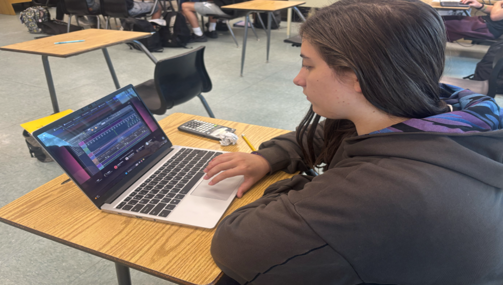 Book to work: Juliette Stricklan works on her book club project on her laptop during class. Stricklan, a student working on her final assignment, had originally chosen Anthem but switched books after finishing it because she preferred a darker theme. The project required students to complete worksheets and participate in discussions, although not all groups followed the same structure. Stricklan explained that “some people decided to work together on their projects but have to do double the requirements” and added that “We didn’t really discuss, but the worksheets were helpful,” showing how her experience focused more on independent work. Photo By Ereny Elrayis