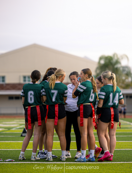 TIMEOUT FOR SUCCESS: With much energy and dedication, Coach Maira Thompson gives the Melbourne High School Varsity Flag Football Team a prep talk before they go into the game. Melbourne High School Varsity Flag Football Team has a record of 3-1. With much teamwork and perseverance, Melbourne High School conquered a win with many touchdowns and passes against West Shore. “Our game was energetic and so much fun to play alongside with the girls” said Bellflower.  Photo by: Enzo Captures      Photo by Enzo Widjaja 