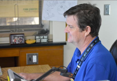 Caption: Harboring Helpful Time with Mr. Hall: Mr. Hall at his computer in building 10 during his lunch period, of lunch B. Mr. Hall has worked in Mel High since 1999 and acquired plenty of experience from having ran clubs, been a coach, and even having taught some current teachers here. “I’ve been a Coach and Sponsor of the Academic team for more than 20 years. Gotten quite used to that. It’s a fun, sorta like a jeopardy, quiz bowl kinda thing.” said Mr. Hall. Photo by Tyler Ferreira Alves Hill.
