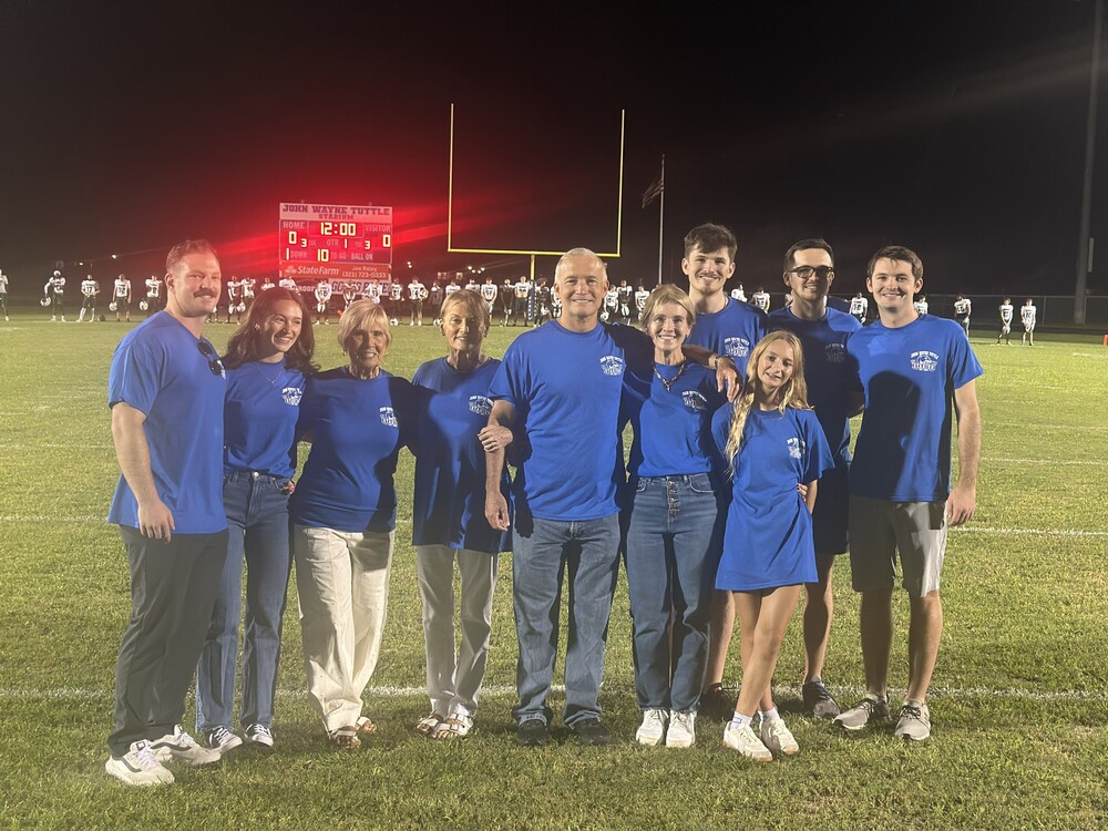 Mr Tuttles family poses on football field as it is named for John  Tuttle, the founding principal
