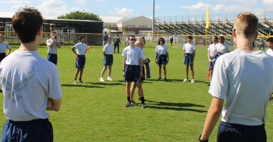 Motivation + Teamwork = A Great Team: Charlie Flight leaders stands in the center of a circle of cadets for their daily motivation chant. “We do motivation checks in the classroom or outside and it keeps the team motivated,” says Hayden Meagher. The flights participated in PT time every wednesday. All members left the classroom and went to the school baseball field and played games such as kickball and modified versions of Capture the Flag. Photo by Kyle McLaren