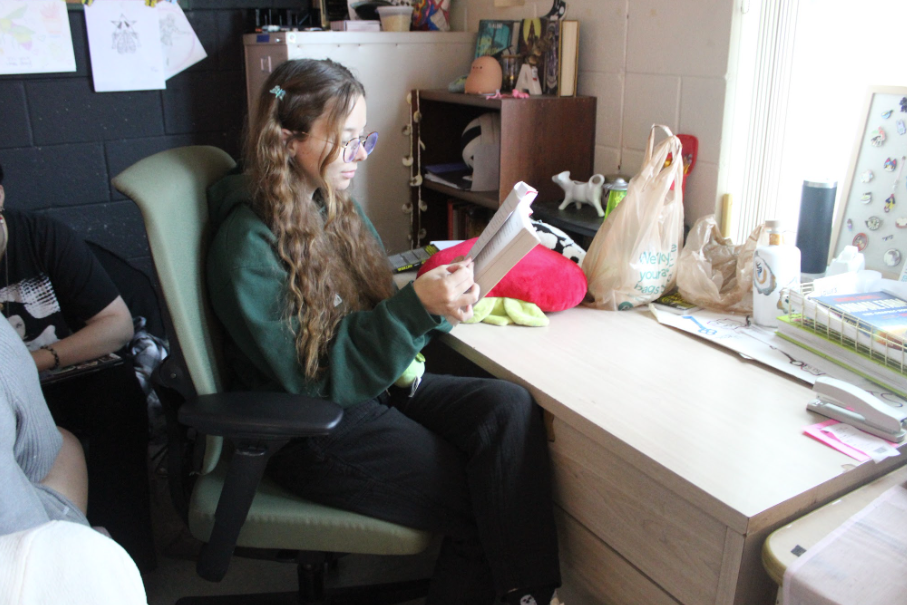  Caption: Turning the Page: Mrs. Melanie Anderson sits in her classroom in Building 1 during 4th period reading a book called “Scythe” as the students work independently. She will leave to pursue her master's degree in library science after this school year. She taught English 1 and Creative Writing at this school for 4 years. Mrs Anderson inspired many students through her passion for learning including sophomore Yael Bachman who said, “She has made a lasting impact upon many students, and I’m glad to know that with whatever happened in the future, she will continue to impact people’s lives for the better.” Photo by Ayaana Gupta