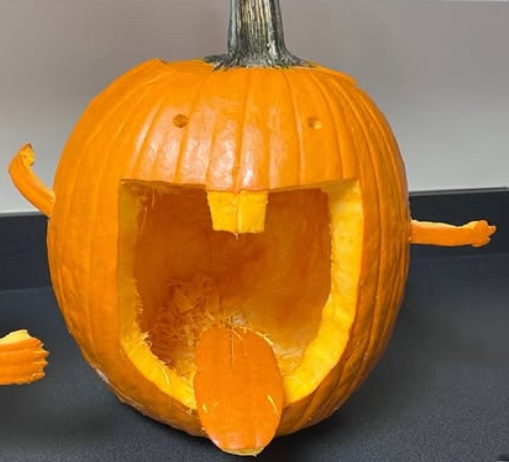 Caption: Pumpkin Masterpiece:Soccer player Aisling O'Donnell’s design showcases a playful, exaggerated expression with a tongue sticking out, arms, and even some funny details that add personality. It’s clear this isn’t your typical jack-o’-lantern. O'Donnell said, “We got our inspo from Pinterest,” and it’s easy to see how inspiration from the site led to this creative, out-of-the-box design. Halloween decorations don’t always need to be traditional. O'Donnell wanted to make it a fun and memorable experience. Photo by Chloe Strong