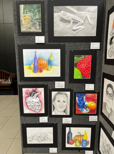 Caption: Teacher Encourages Student Creativity: Ms. Robb chats with students at the Melbourne High School art show at the Melbourne Mall. She helps guide students and supports them as they explore different art styles. The show gives students a chance to share ideas and get inspired by each other. Many students walked around looking at a variety of techniques, from painting to mixed media, and talked about what they liked most. Ms. Robb says she loves seeing students grow through their work. “I am always inspired and in awe of my students’ artwork,” Ms.Robb said. She also mentioned that events like this help students feel proud and confident in their creativity. The exhibit encourages students to experiment and try new ideas for future projects. Photo By Carolyn Robb