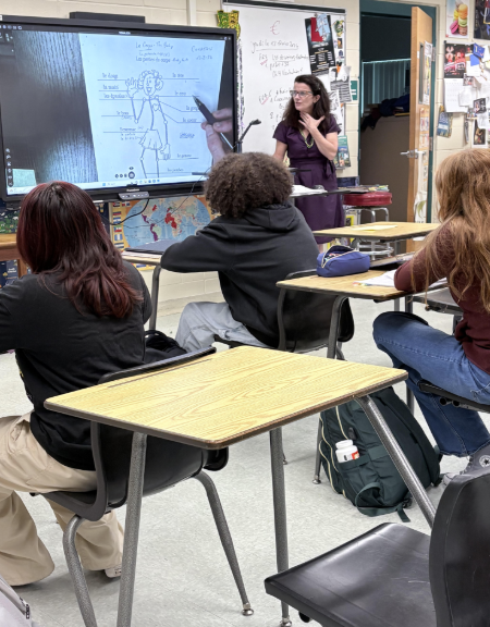 Madame Courtois stands at the front of the classroom, pointing to a diagram on the board as students follow along during French class. Sophomore Kamryn Travers shares her appreciation, saying, “I think that Madame is the best teacher I have ever had.” Photo by: Brooke Johnson