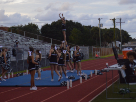 Caption: Sideline Support: At the Melbourne high school JV football game, Ally Field and the JV cheer team supports the football team. The cheerleaders perform stunts and routines at every game to boost school spirit and pride. The football team won the game 20-6 against Rockledge high school with the support of the cheer team and fellow students. “Cheerleading boosts school spirit because everyone's smiley and it brings joy,” Field said. Photo by Lily Hock.