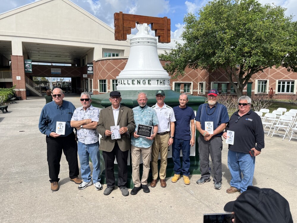 Select community members, alumni and staff of Melbourne High stand in front of the Liberty Bell