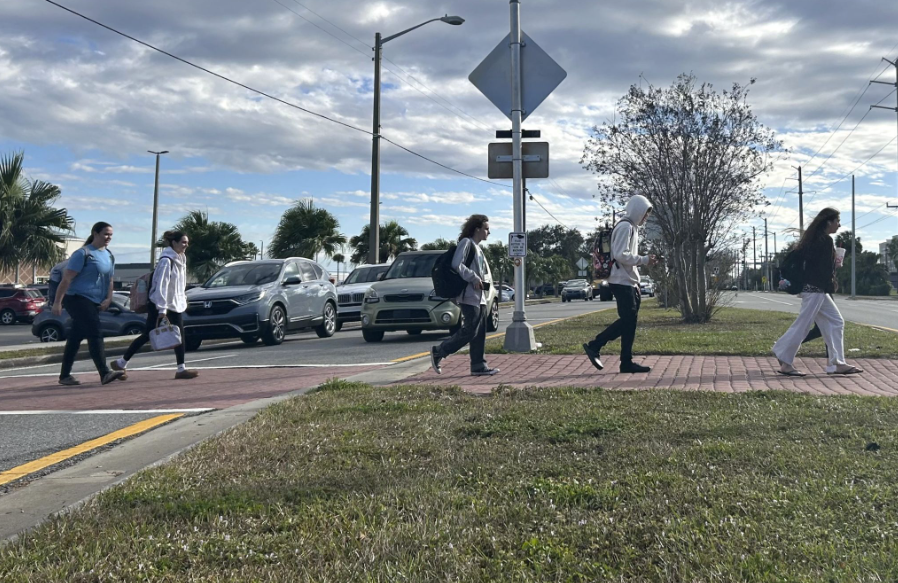 Caption: Press to Walk: Before and after school, some students cross Babcock Street using the crosswalk in front of Starbucks. “I use the crosswalk for safety reasons, and because I take the bus”. said Milan Hadley. “I cross to get from the Starbucks. I usually order an Acai Refresher,” Maddie Toenjes said. Kateryna Paryhina used the crosswalk to get from her apartment to the school. “I like living next to the school. I leave five minutes before the first bell,” said Paryhina. The Babcock Street crosswalk was one of three crosswalks near the school where students crossed at to get to places such as Starbucks, the Melbourne Shopping Center, or the SCAT bus stops. Photo by Kyle McLaren