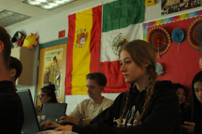 Caption: Focused, And Ready: Gracie Forney, an 11th grade student, works on a Spanish assignment for her class earlier this semester. The assignment asked students to design a restaurant menu in Spanish using different foods from Hispanic cultures. Students completed the project online while  they researched dishes and practiced Spanish vocabulary. The activity helped them learn more about culture while being creative with their designs. “I liked having different countries for all my dishes, making options for everyone,” Forney said Copy by: Paige Allen Photo by: Paige Allen