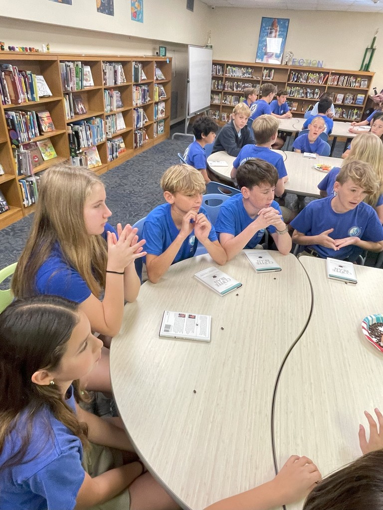 Students at Freedom 7 sit at a table and chat surrounded by copies of The Coffee Bean