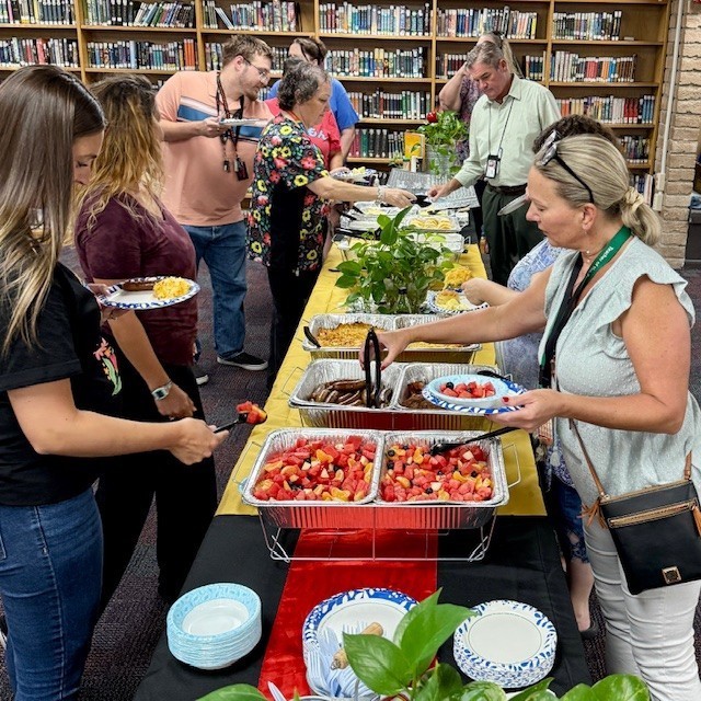 staff standing in front of a buffet line reaching for food and filling their plates