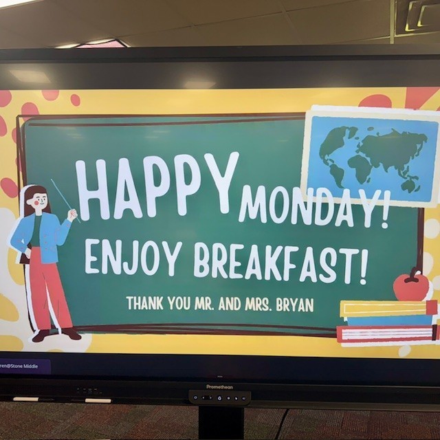 teacher standing in front of a chalkboard that says happy monday enjoy breakfast thanl you mr. and mrs. bryan