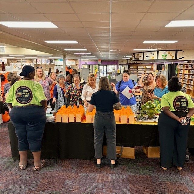 staff waiting in line and receiving their cupcakes from dana's cupcake owners and principal williams