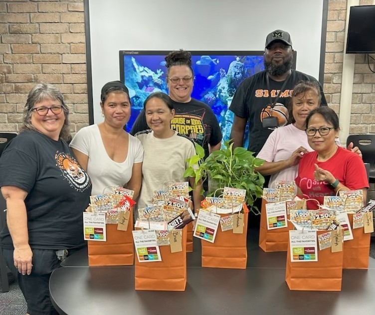Image of people standing around a table smiling with gift bags