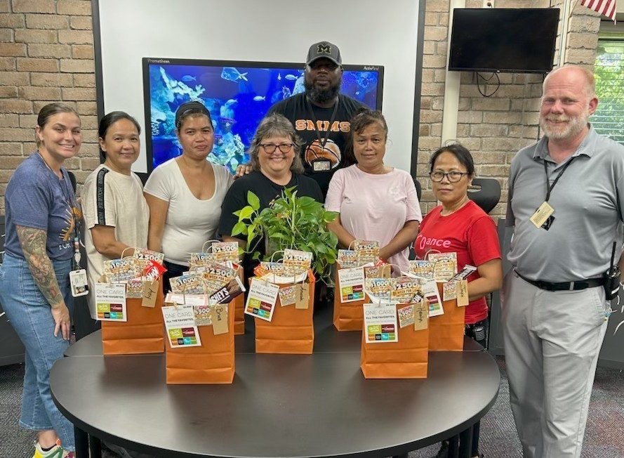Image of people standing around a table smiling with gift bags