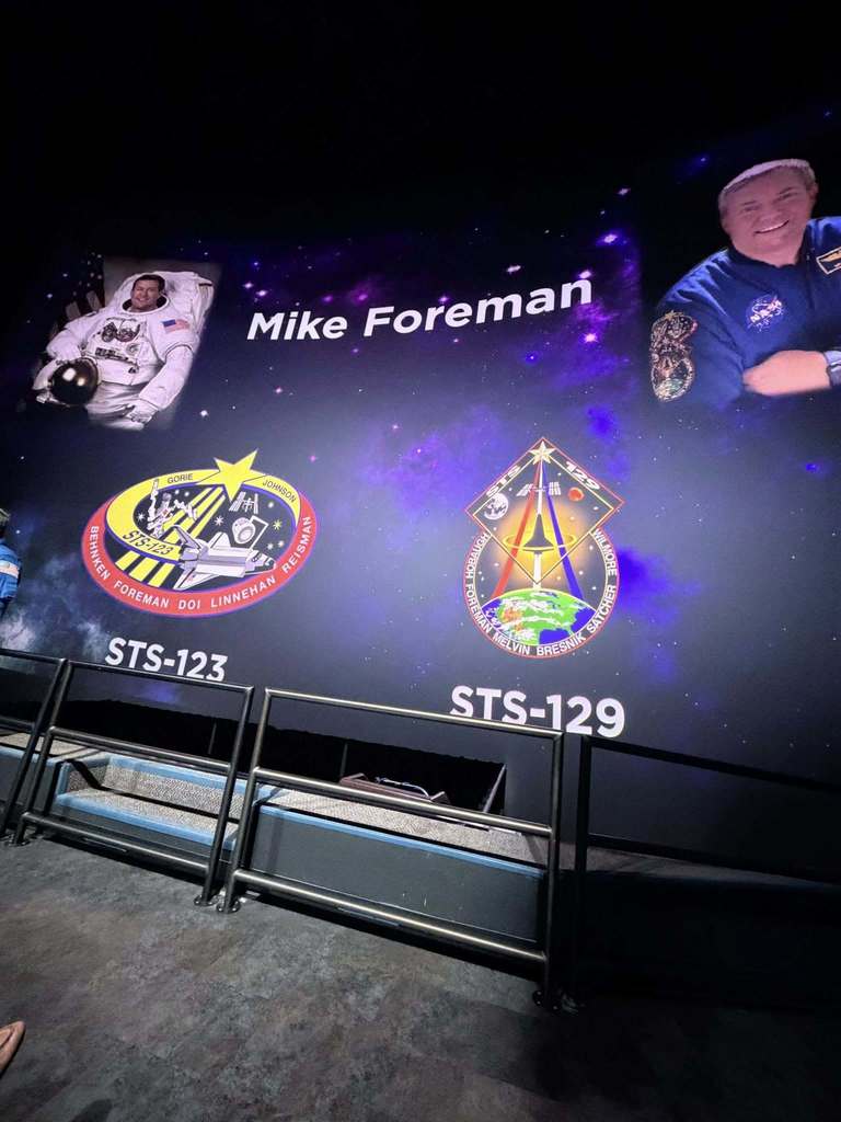 A slide of astronaut Mike Foreman with pictures of him and the patches for the missions he flew
