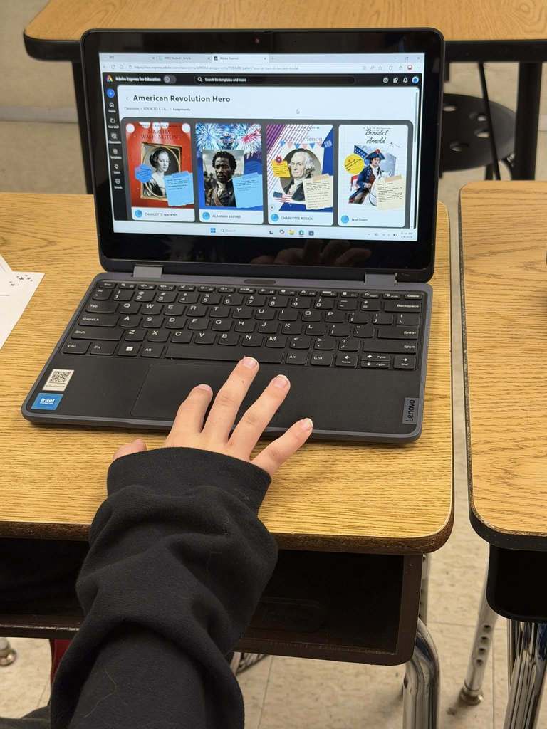 Students sitting at desks with laptops using Adobe for Education Express as a tool to show their learning