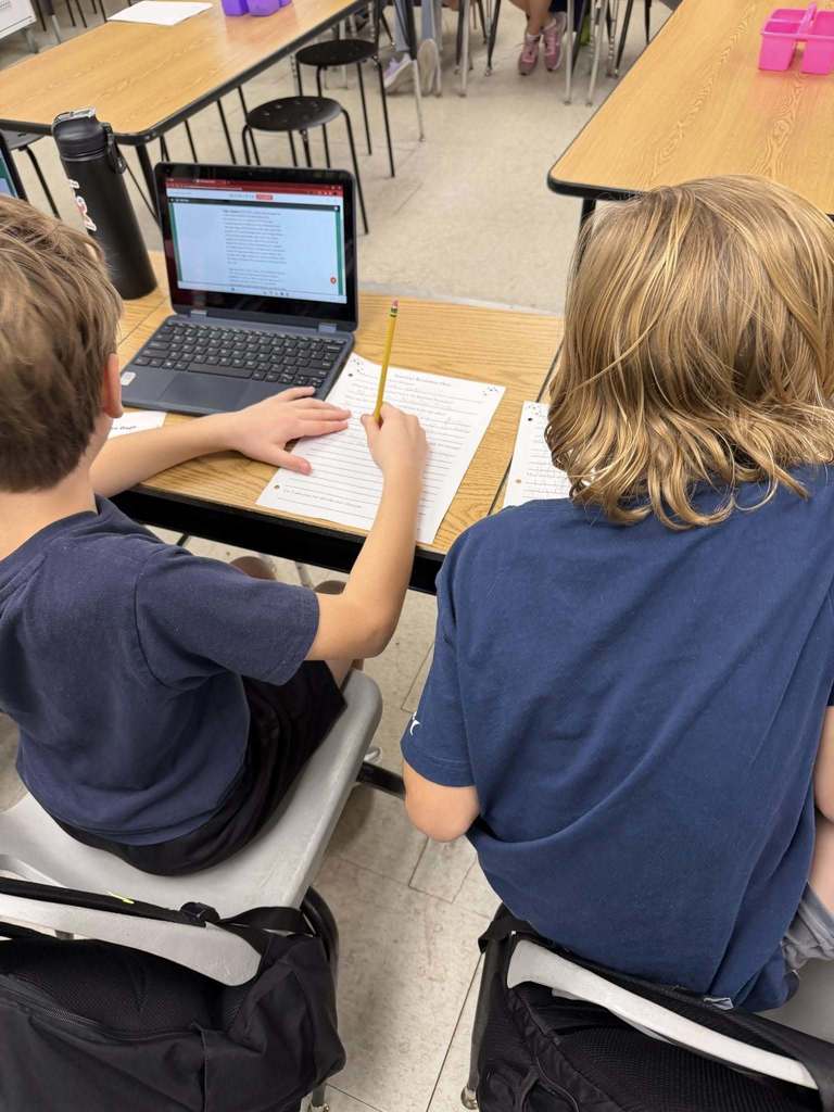 Students sitting at desks with laptops using Adobe for Education Express as a tool to show their learning