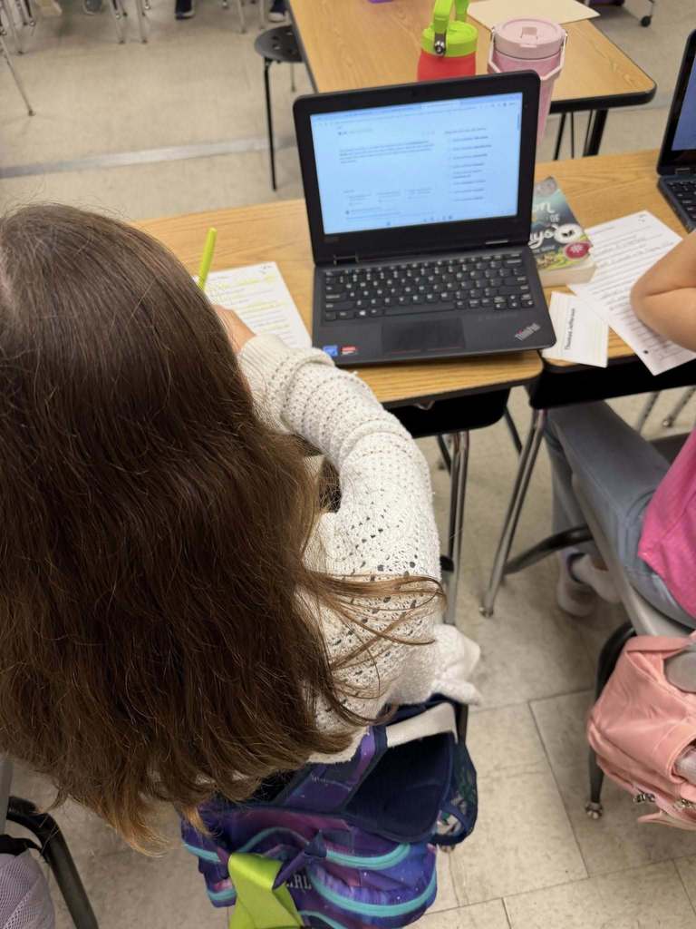 Students sitting at desks with laptops using Adobe for Education Express as a tool to show their learning