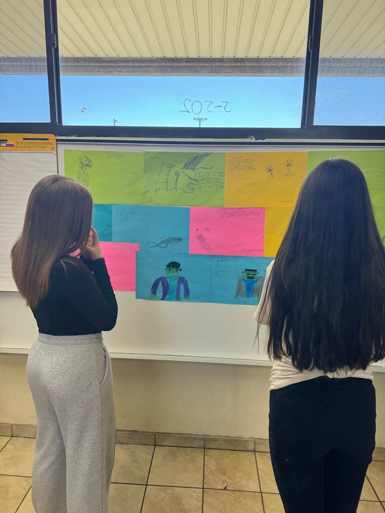 picture of students looking at hangings on the wall  of student created art