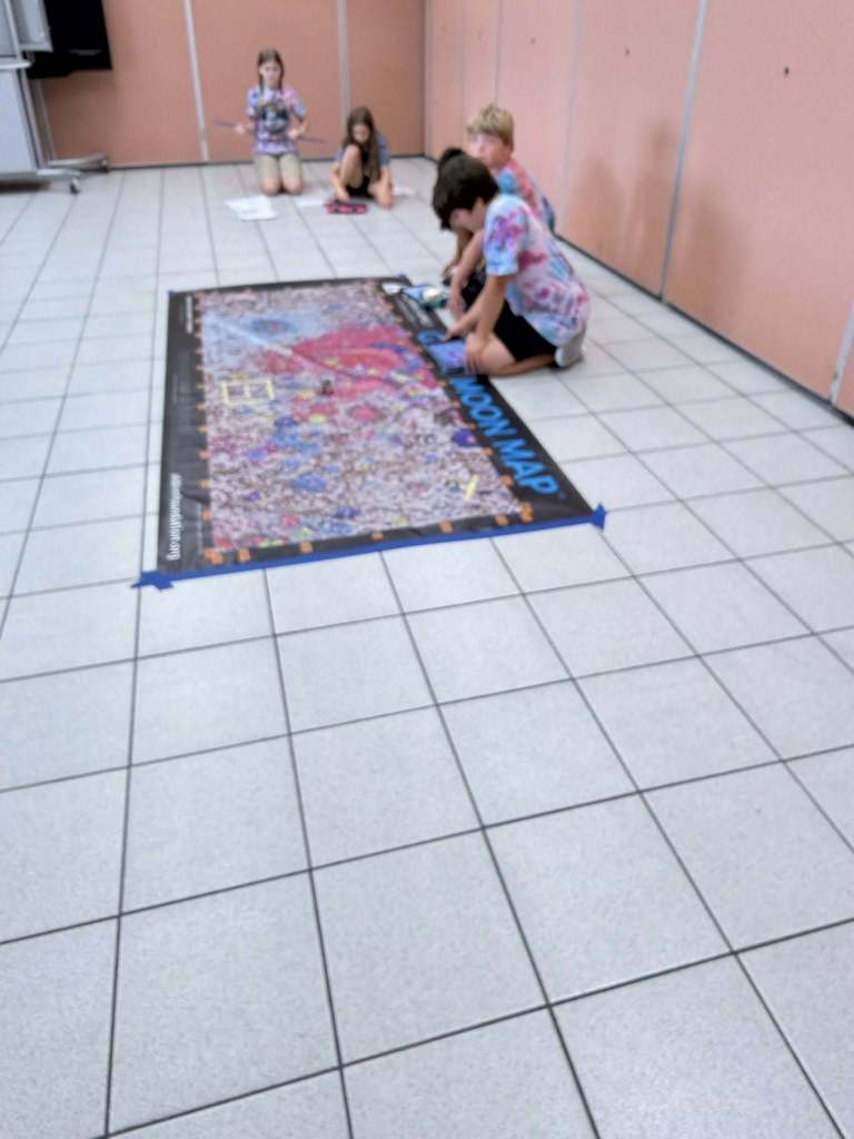 students showing off their spike prime robot on a map of the moon