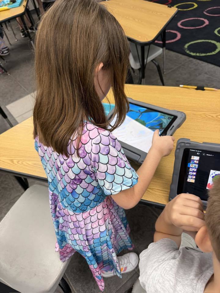 A student taking a picture of their plant with an iPad